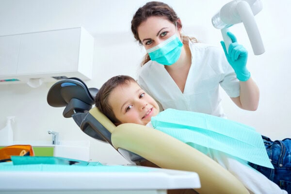 Beautiful kid boy smiling in dentists chair the office treats teeth.