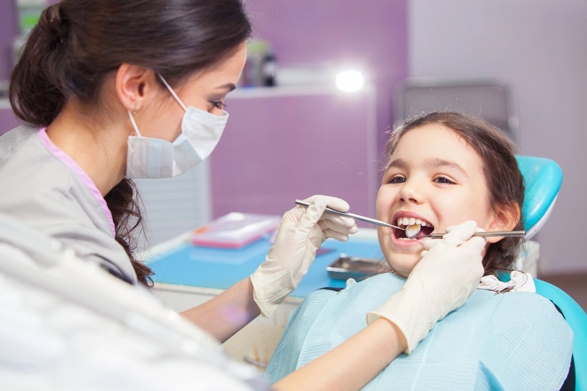 Close-up of pretty little girl opening his mouth wide during treating her teeth by the dentist